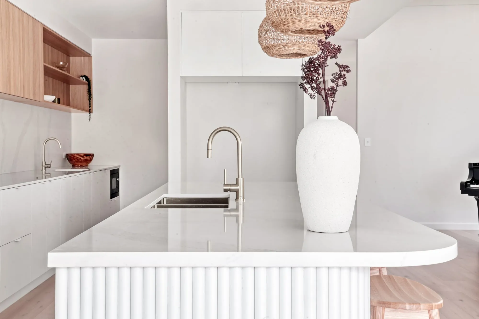 Kitchen with a white stone island on a fluted base and timber open shelving
